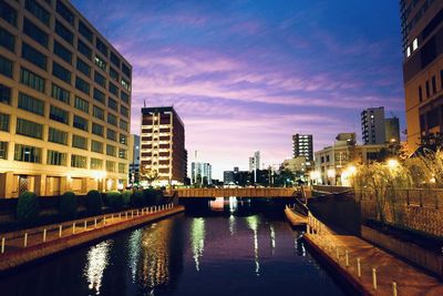 Bridge over canal amidst buildings in city at dusk