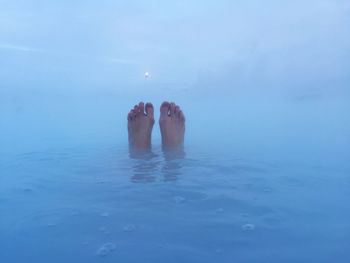 Low section of person relaxing in blue lagoon
