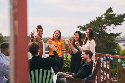 Happy friends toasting drinks on terrace during party