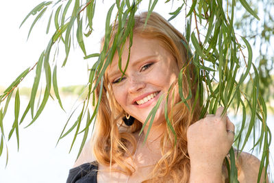Portrait of smiling teenage girl standing by leaves