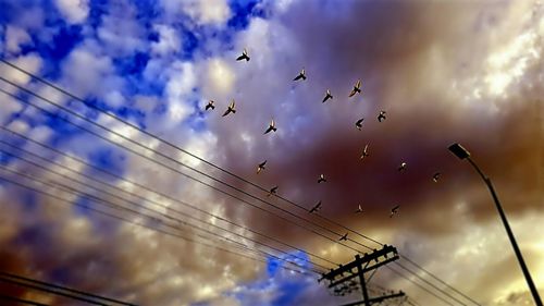 Low angle view of power lines against cloudy sky