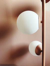 Close-up of light bulb hanging from ceiling next to dusk pink wall