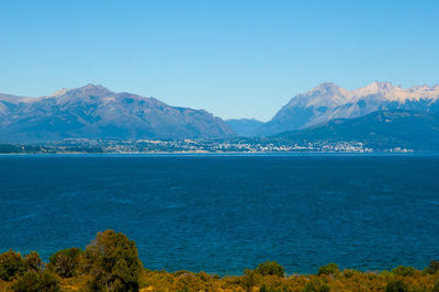 Scenic view of sea and mountains against clear blue sky