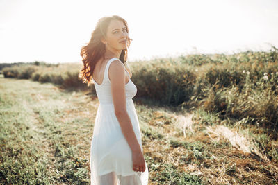 Side view portrait of smiling beautiful young woman standing on land during sunny day