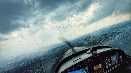 Close-up of water drops on airplane against sky