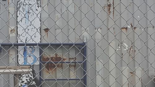 Corrugated iron seen through chainlink fence