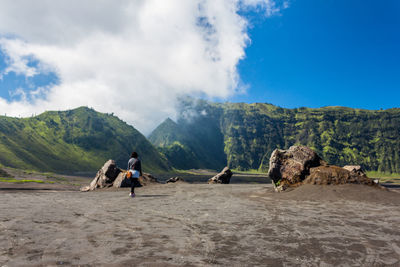 Panoramic view of people on landscape against cloudy sky