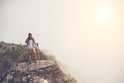 Female hiker standing on cliff during foggy weather