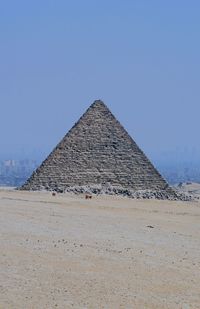 View of desert and pyramid against clear sky