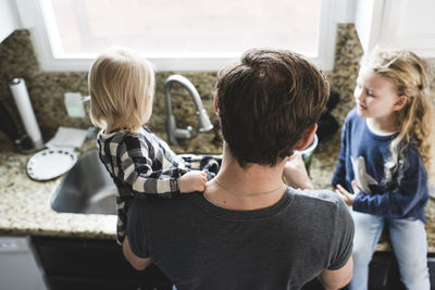 High angle view of father with daughters cooking food in kitchen at home