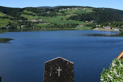 Scenic view of lake by buildings against sky with gravestone in fore front.