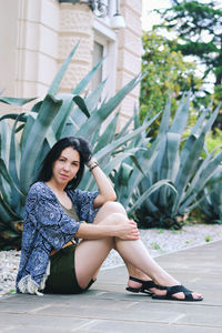 Portrait of young woman sitting on footpath