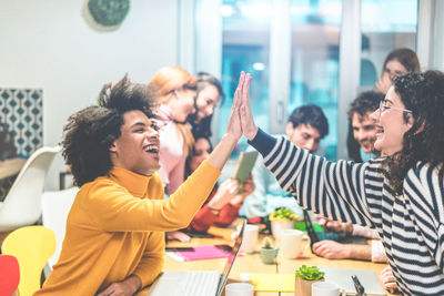 Cheerful colleagues giving high five in office