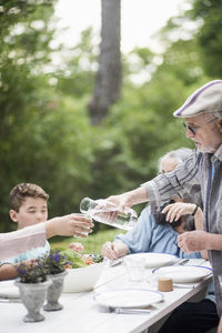 Senior man pouring water for woman at back yard