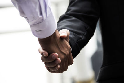 Midsection of business people giving handshake at office