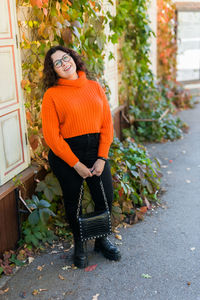 Young woman standing against plants