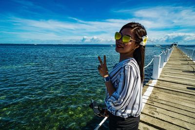 Woman wearing sunglasses against sea against sky