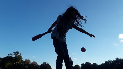 Low angle view of people playing against blue sky