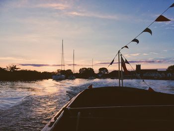 Boats sailing in sea against sky during sunset