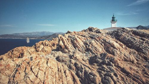 Lighthouse amidst buildings and mountains against sky