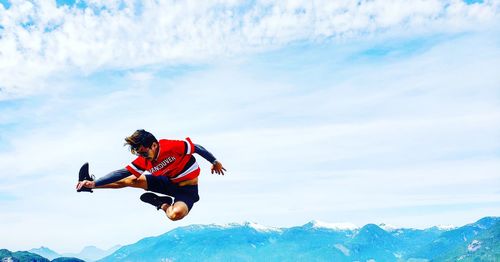 Man jumping in mountain against sky