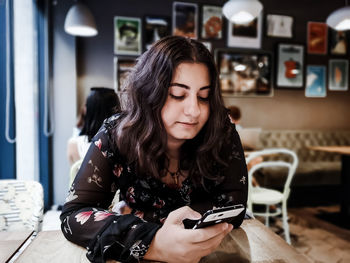 Young woman using mobile phone while sitting in laptop