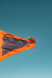 Low angle view of flag against clear blue sky