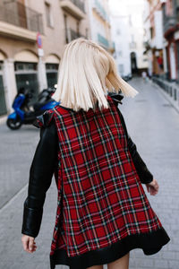 Rear view of woman standing on street in city