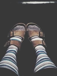 Low section of man standing against black background