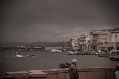 Rear view of man in sea against sky in city