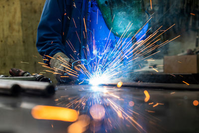 Midsection of person grinding metal in workshop