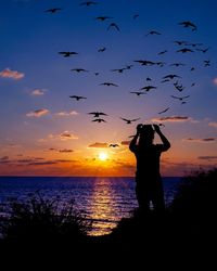 Silhouette man standing on beach against sky during sunset