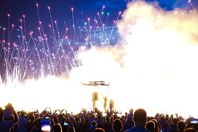 Crowd at music concert against sky at night