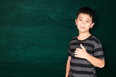 Portrait of boy standing against wall