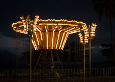 Low angle view of illuminated carousel against sky at night