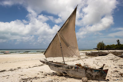 Sailboats moored on beach against sky