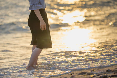 Low section of woman standing in sea