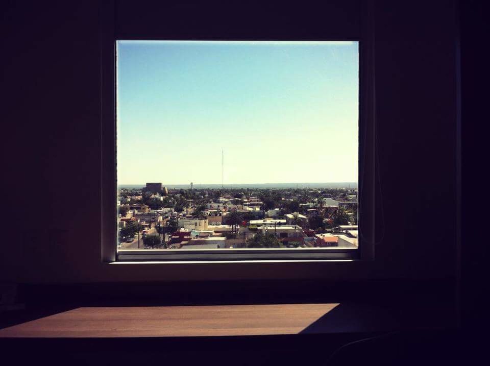 indoors, window, architecture, built structure, cityscape, transparent, building exterior, city, glass - material, clear sky, residential structure, house, crowded, looking through window, residential building, residential district, copy space, home interior, sky, day