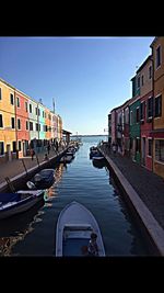 Canal amidst buildings in city against clear sky