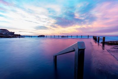 Pier on sea against sky at sunrise