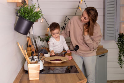 Young woman and little son play in the kitchen with dry red beans, together