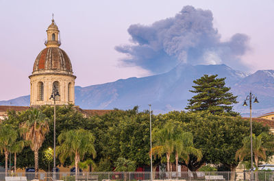 Low angle view of the cityscape against the sky during the strombolian eruption of etna