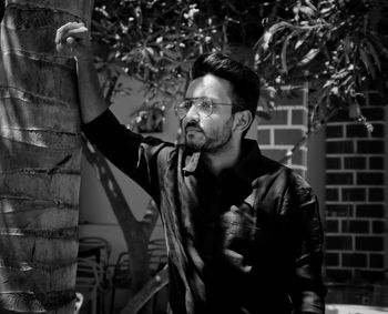 Portrait of young man standing against plants