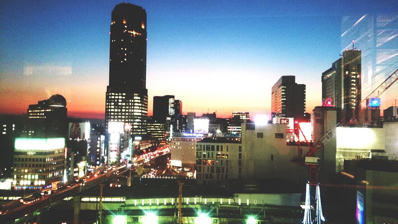 ILLUMINATED SKYSCRAPERS AGAINST SKY AT DUSK