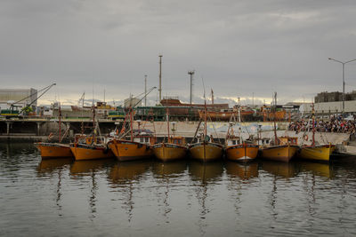 Boats moored at harbor against sky