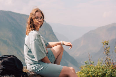 Side view of woman sitting on mountain