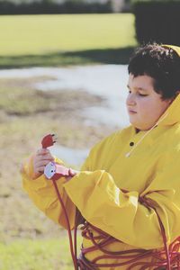 Boy wearing raincoat wrapped with cables standing outdoors