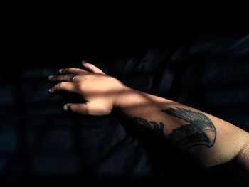 Cropped hand with tattoo in darkroom