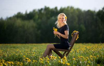 Portrait of beautiful woman sitting on chair at field