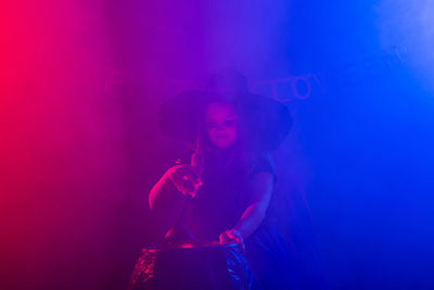 Full length of woman standing against illuminated wall